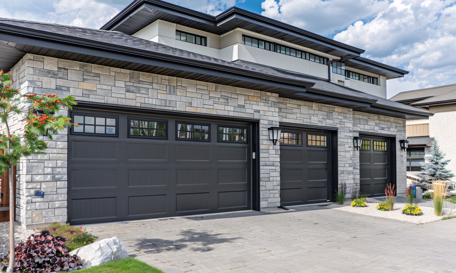 Modern home exterior with stone facade and dark garage doors, exemplifying high-quality craftsmanship suitable for Bay Area home renovations.